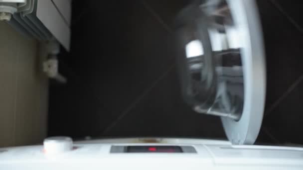 Девушка загружает белье в стиральную машину, вид сверху — стоковое видео