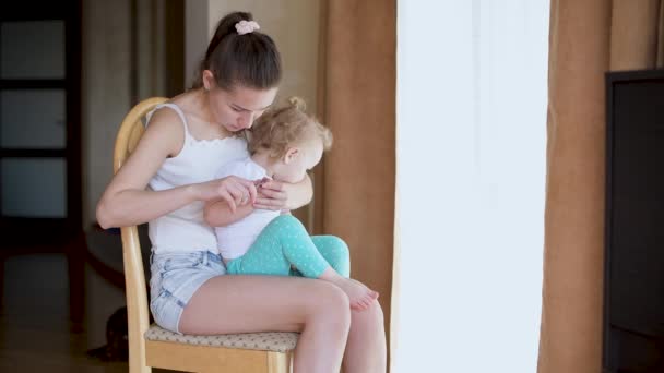 Una joven madre cuida las uñas de una pequeña hija inquieta — Vídeo de stock