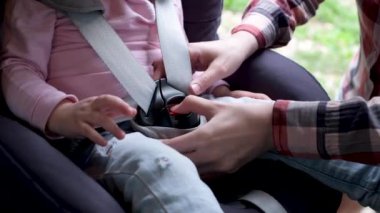 Anne çocuğunun bağlarını çözer ve onu çocuk koltuğundan çıkarır.