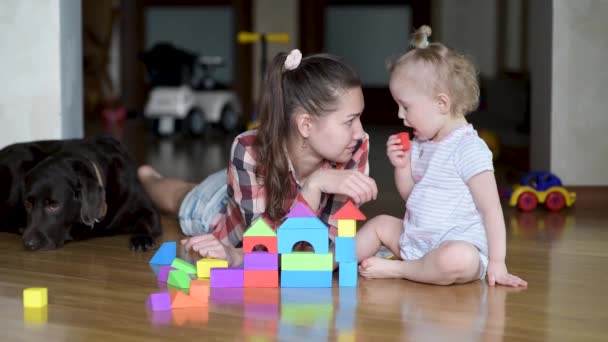 Mamma leker i färgglada figurer med en liten dotter på golvet — Stockvideo