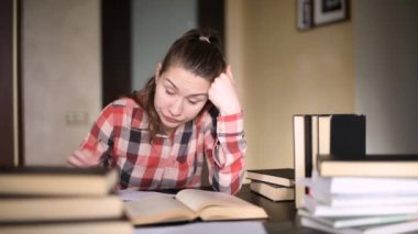 Öğrenci kız çalışmaktan yoruldu, gözlüğünü çıkardı ve elleriyle yüzünü ovuşturdu.