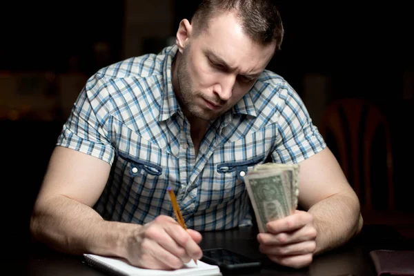 Ένας Άντρας Σοβαρό Πρόσωπο Κρατάει Λεφτά Και Κρατάει Σημειώσεις Ένα — Φωτογραφία Αρχείου