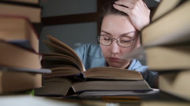 Uma jovem com óculos adormece sobre um livro didático no final da noite — Vídeo de Stock