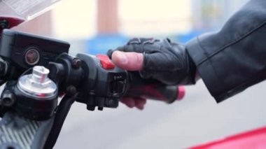 Motorcu elini motorun gaz koluna koyar, kontağı açar ve motoru çalıştırır. Yakın plan el.