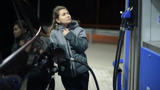 Молодая женщина на заправке ждет заправку своей машины — стоковое видео