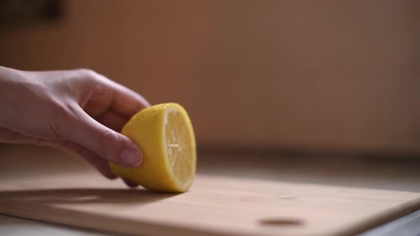 Fiatal nő szeletel egy citromot a konyhaasztalon — Stock videók