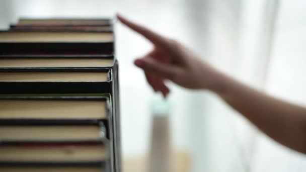 Meisjes hand selecteert een boek en neemt het van de plank — Stockvideo