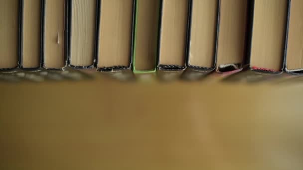 Blick von oben auf ein Bücherregal und ein Mädchen nimmt eines der Bücher — Stockvideo