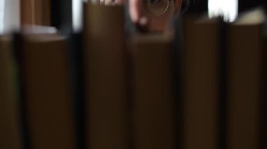 Kız öğrenci bir kitap seçiyor ve raftan alıyor.