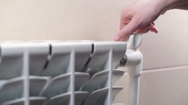 Kız evdeki bataryayı kapatıyor ya da ısıtıyor.