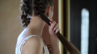 Genç bir kadın koridorda aynanın önünde örgü örüyor, yakın plan.