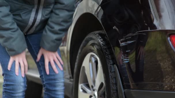 Dívka si všimne čerstvých škrábanců na nárazníku auta a je naštvaná — Stock video