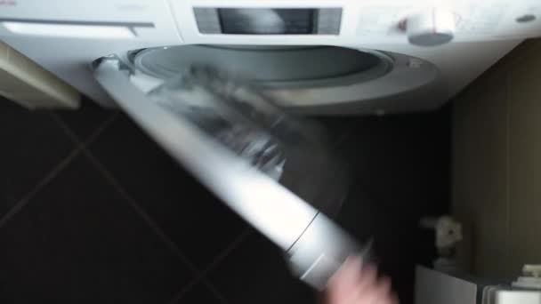 Девушка кладет белые полотенца в стиральную машину и запускает прачечную — стоковое видео