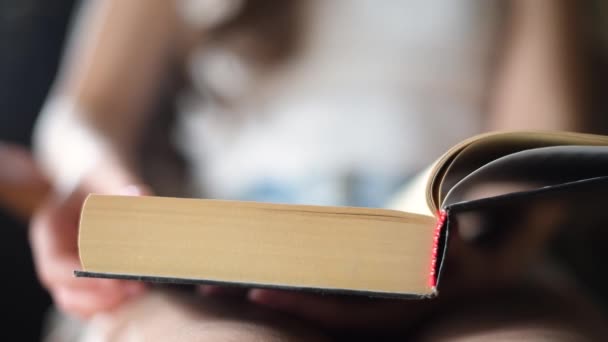 Chica hojeando a través de una página de un libro de papel, primer plano — Vídeo de stock