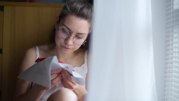 一个戴眼镜 在窗边绣十字绣的女孩的特写镜头 — 图库视频影像
