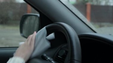 Kız salgın sırasında araba direksiyonunu antibakteriyel mendille siliyor.