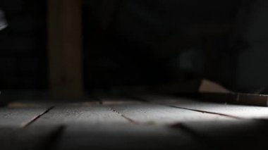 Tavan arasındaki tozlu ahşap zemine bir bot basar ve tozu havaya kaldırır. Kapat.