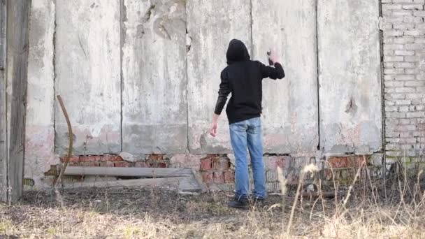 若い男が通りの古い壁にスプレーを塗ります 放棄された建物と破壊 — ストック動画