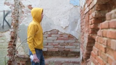 Bir genç, terk edilmiş bir binanın duvarına sprey boya çiziyor.