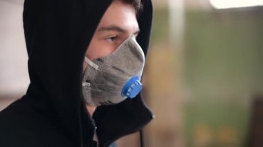 Solunum cihazlı ve kapüşonlu bir adamın yan görüntüsü.