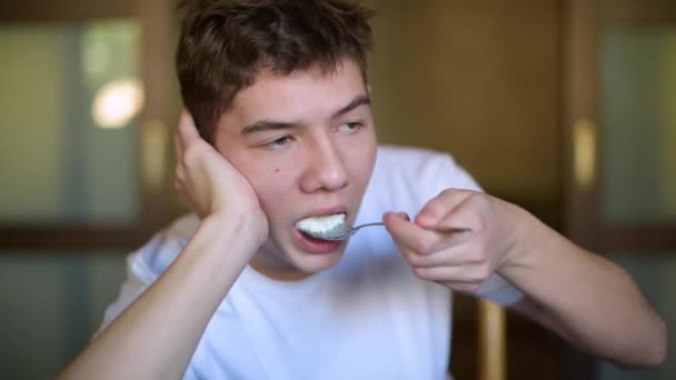 Nastolatek Leniwie Wkłada Ryż Owsianka Jego Usta Żuje Zbliżenie — Wideo stockowe