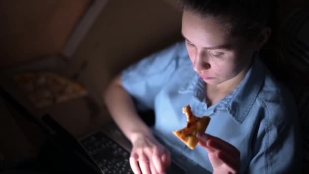 一个女孩的特写镜头 她吃披萨 深夜在笔记本电脑上工作 — 图库视频影像