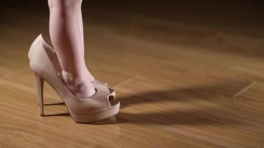 Kadın ayakkabısı giymiş çocuk ayaklarına yakın çekim. Bir kız annesinin ayakkabılarını giyiyor.