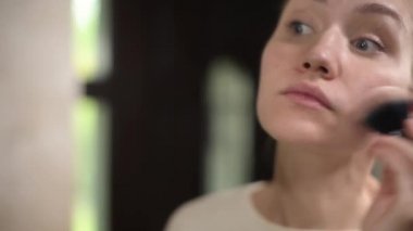 Kız aynanın önünde makyaj yapıyor. Kamera yansımadan kıza ve geriye doğru hareket eder. Bulanık, seçici odaklanma