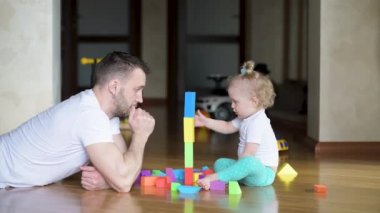 Babam küçük bir kızla oynuyor. Baba ve bebek yere renkli figürlerden bir kule inşa ederek harika zaman geçiriyorlar.