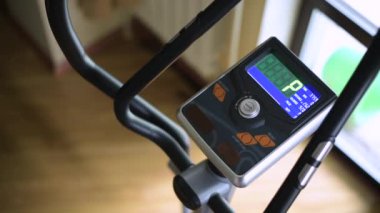 Kız programa elipsoidle başlıyor ve eğitime başlıyor. Makine kontrol panelinin görüntüsü. Evde spor ve spor