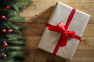 Ahşap bir masa üzerinde ladin dalları. Tahtanın üstündeki Noel süsleri yukarıdan görülüyor. Reklam ürünleri, dekorasyonlar ve metin için yer.