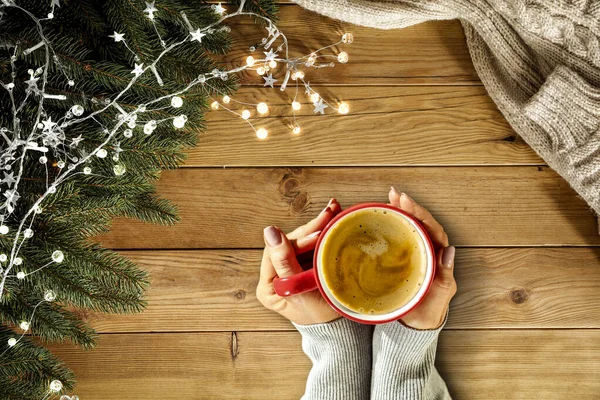 ホットドリンクを手に女性の手のトップビュー あなたの装飾のための自由なスペース ホットチョコレートやコーヒーのカップ テーブルの上のクリスマスの背景 クリスマスだコピースペース 空中ビュー 影のある暗いムードの光 — ストック写真