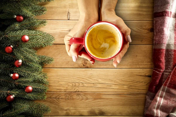 ホットドリンクを手に女性の手のトップビュー あなたの装飾のための自由なスペース ホットチョコレートやコーヒーのカップ テーブルの上のクリスマスの背景 クリスマスだコピースペース 空中ビュー 影のある暗いムードの光 — ストック写真