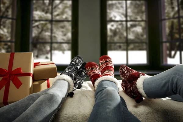 Woman legs in woolen socks. Wooden winter background with free space. Christmas december time and winter landscape outside the window.