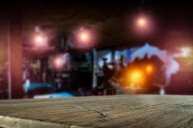 Bar restoranının arka planı bulanık ve reklam ürünleri için yeri olan eski kahverengi ahşap masa üstü. Bulanık ışık arkaplanı.