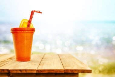 Okyanus ve kumsalın arka planında, tahta masada soğuk bir içecek. Reklam ürünleri için yer kopyala. Güzel güneşli yaz zamanı ve dinlenme.