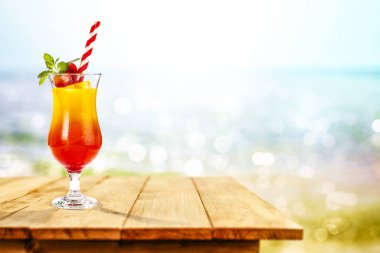 Okyanus ve kumsalın arka planında, tahta masada soğuk bir içecek. Reklam ürünleri için yer kopyala. Güzel güneşli yaz zamanı ve dinlenme.