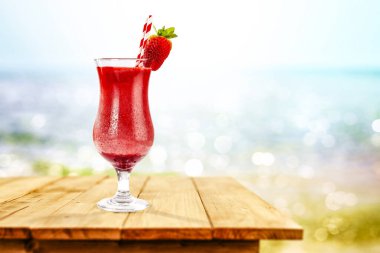 Okyanus ve kumsalın arka planında, tahta masada soğuk bir içecek. Reklam ürünleri için yer kopyala. Güzel güneşli yaz zamanı ve dinlenme.