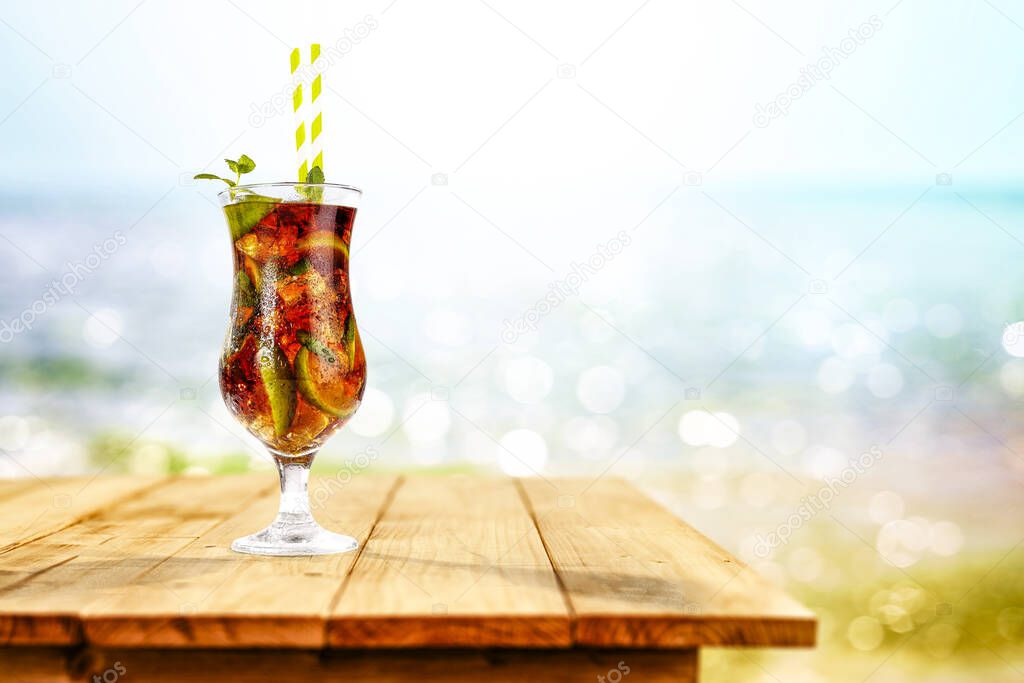 Cold drink on wooden table with ocean and sandy beach background. Copy space for advertising product. Beautiful sunny summer time and relaxation.