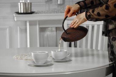 Kadın çaydanlığa çay dolduruyor, yakın plan.