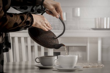 Çaydanlıktan fincana çay dolduran kadın