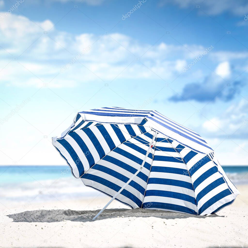Blue and white umbrella on beach. Free space for your decoration. Summer sunny day. Blue sky and ocean landscape. Summer time background. 