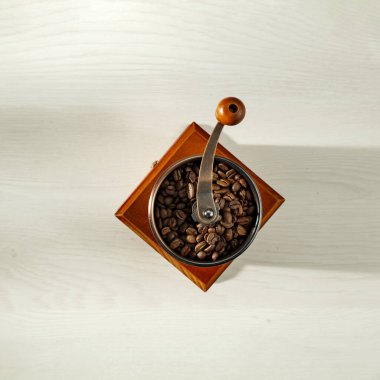 Kahverengi kahve çekirdekleri ve kahve öğütücüsü yukarıdan görülüyor. Beyaz arkaplanlı kahve. Uzayı kopyala Reklam ürünleri için alan.