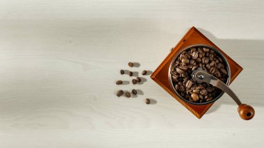 Kahverengi kahve çekirdekleri ve kahve öğütücüsü yukarıdan görülüyor. Beyaz arkaplanlı kahve. Uzayı kopyala Reklam ürünleri için alan.