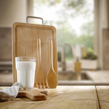 Mutfak gereçleri ve aletleri ahşap masada ve bulanık mutfak arka planında.