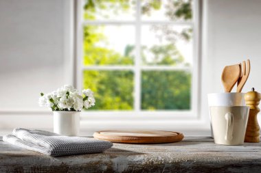 Beyaz çiçekli mutfak masası ve parlak pencere zeminli mutfak aletleri..