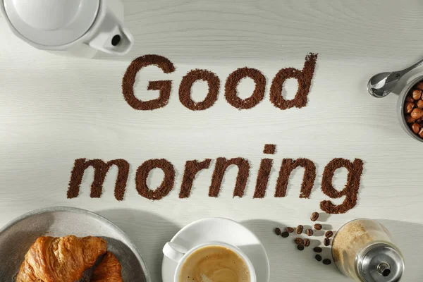 Yazı. Beyaz ahşap masadaki kahve çekirdeklerinden yapılmış günaydın. Kahve zamanı ve yeni bir gün için iyi bir başlangıç. Güzel sabah ve kahvaltı zamanı..