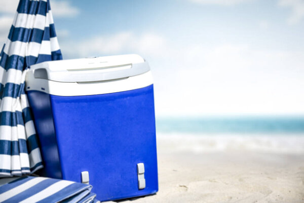 Summer photo of beach and blue beach fridge with umbrella. Sunny day and ocean landscape. 