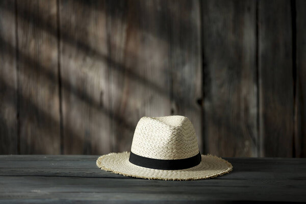 Деревянный стол с местом для украшения. Состав соломенной шляпы с деревянной ретро стеной и тенями солнечного света. Копирование пространства для украшения. 