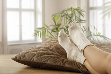 Bacaklar masanın üzerinde çoraplar ve bahar güneşi pencerenin dışında.